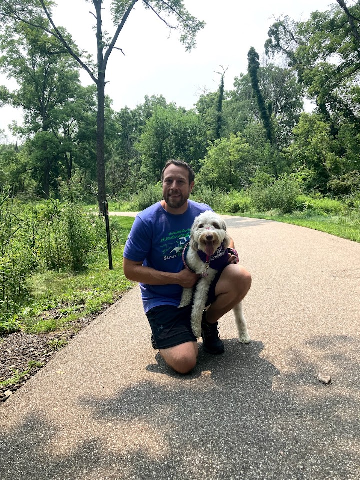 Chris kneeling outdoors with his dog Barbara