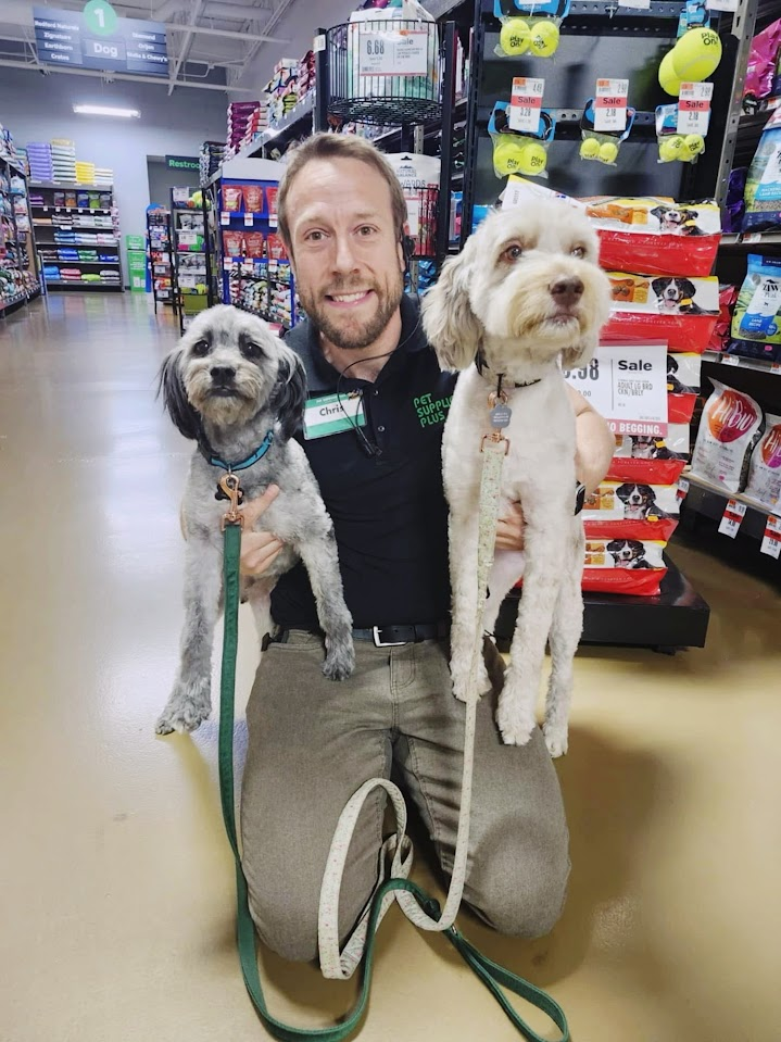 Chris Brennan kneeling in a pet store while holding two dogs