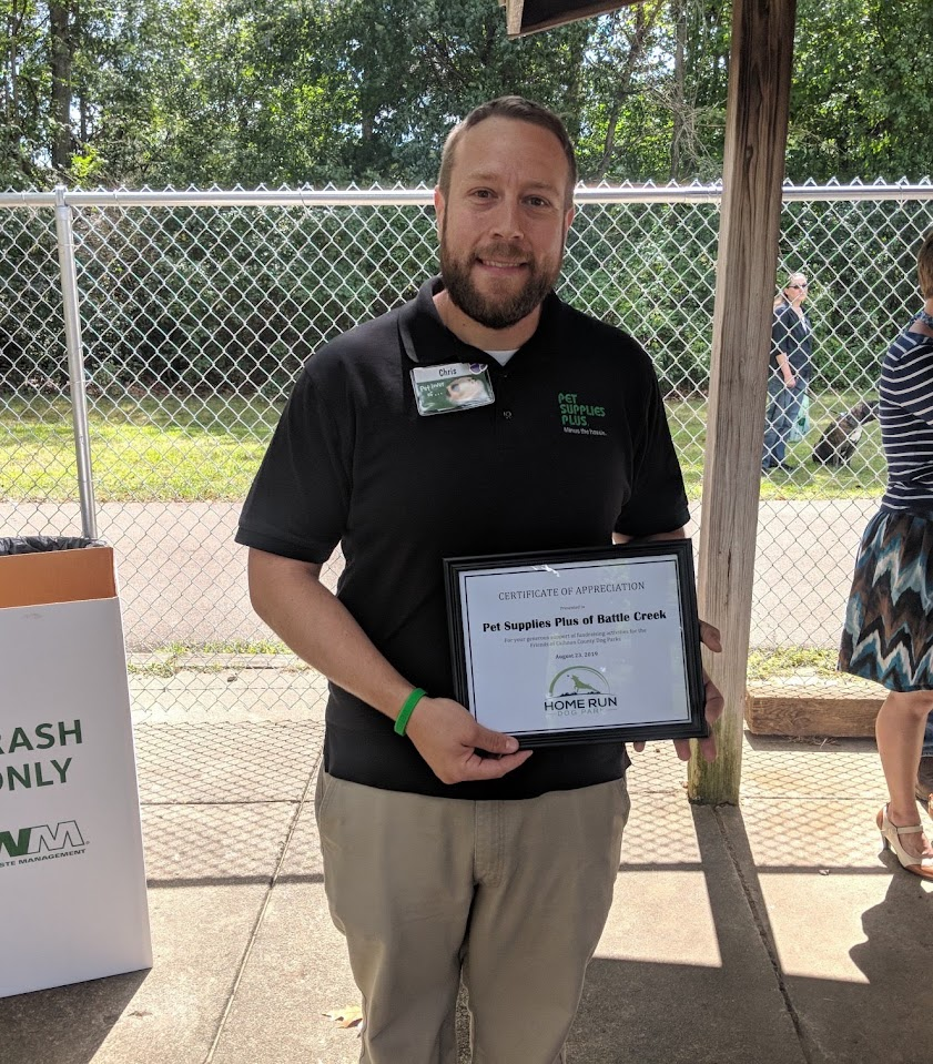 Chris Brennan holding a community appreciation certificate for Pet Supplies Plus of Battle Creek