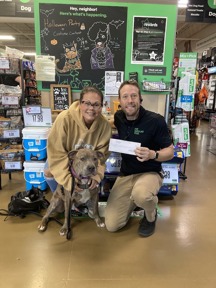 Chris Brennan presenting a donation to Sabrina’s Light Rescue with a rescue representative and dog